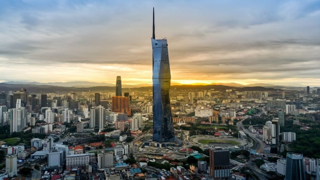 A tall glass skyscraper above the city at sunset